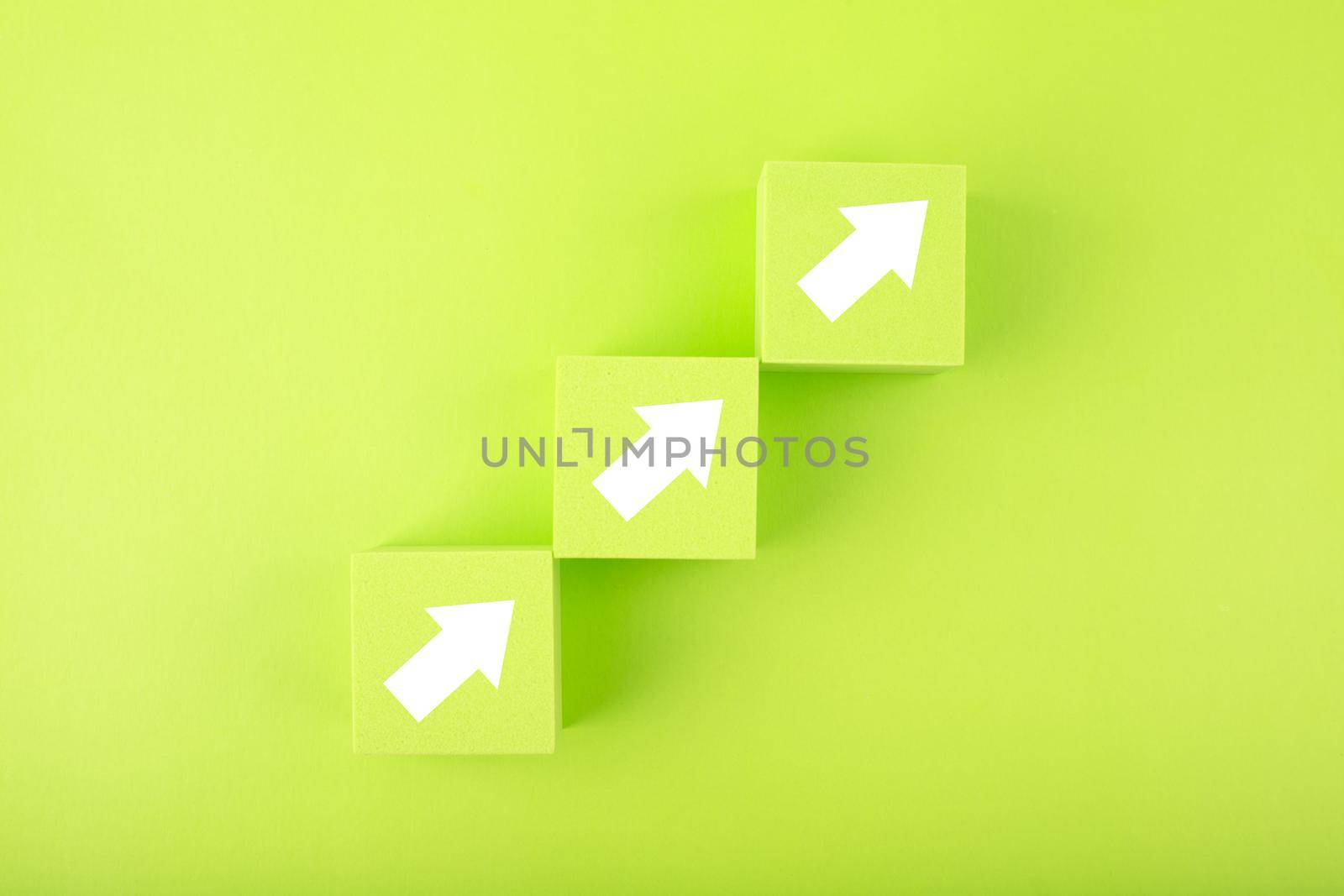 Ladder career, sales or business growth and success path concept. Green blocks as step stairs with white arrows up on bright background with copy space