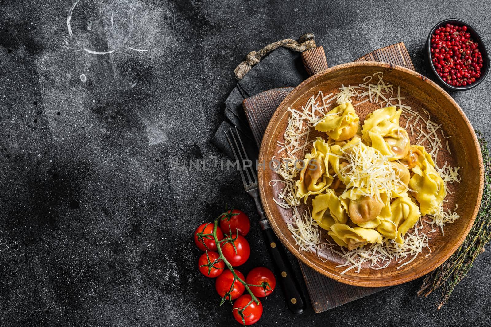 Italian ravioli Pasta with Mozzarella cheese and Tomato in wooden plate. Black background. Top view. Copy space by Composter