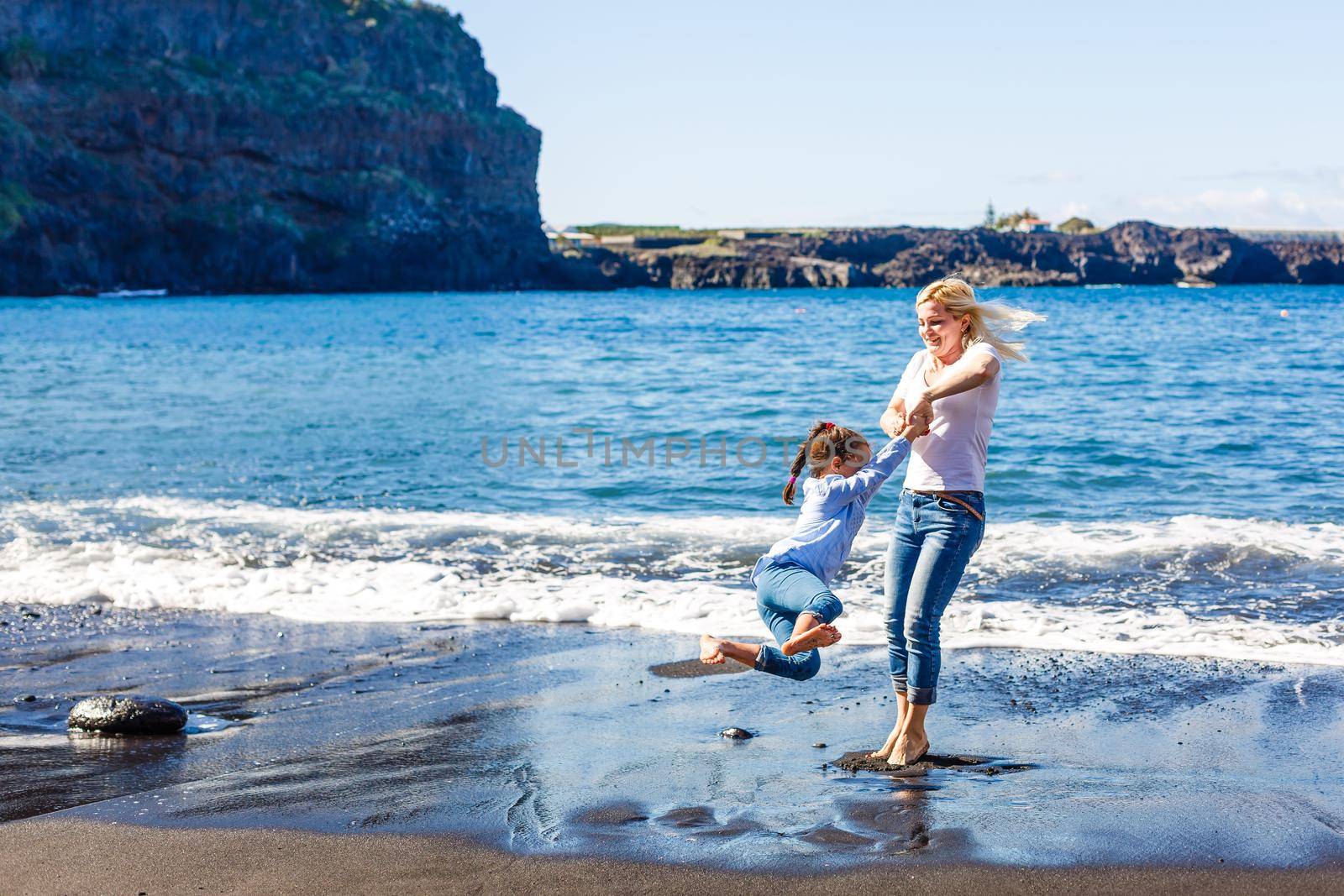 Family holiday on Tenerife, Spain. Mother with daughter outdoors on ocean. Portrait travel tourists - mom with daughter. Positive human emotions, active lifestyles. Happy young family on sea beach