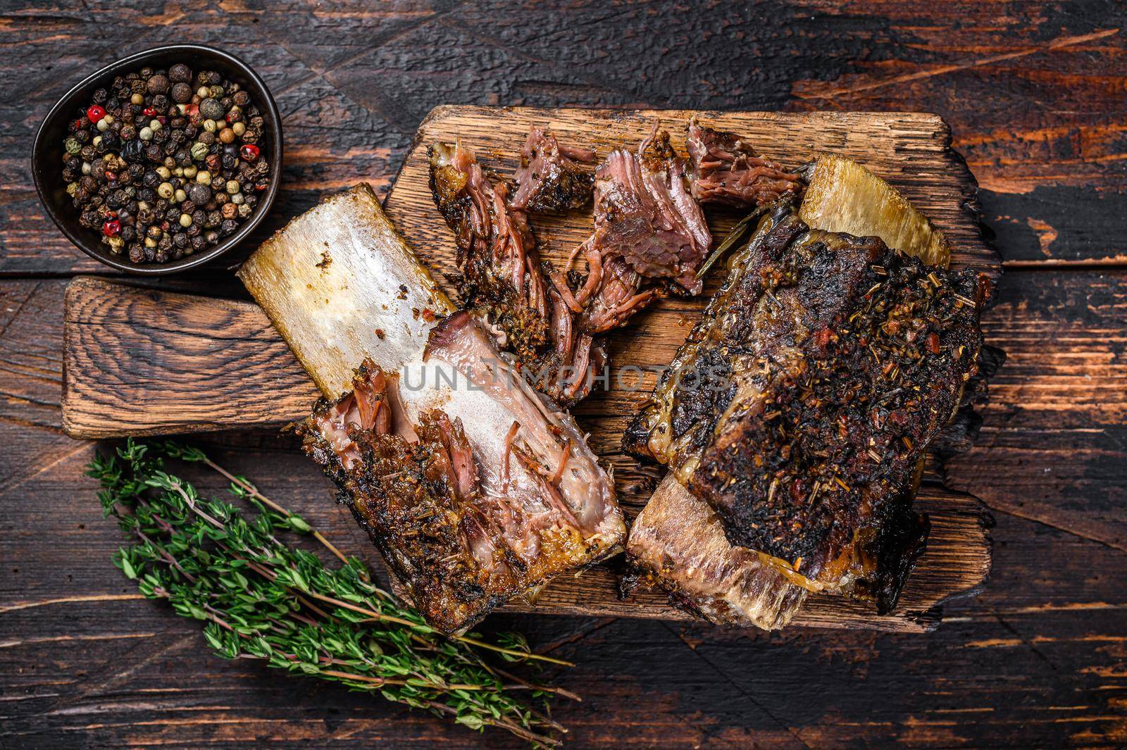 BBQ short chuck beef ribs with herbs and meat cleaver. Dark wooden background. Top view.