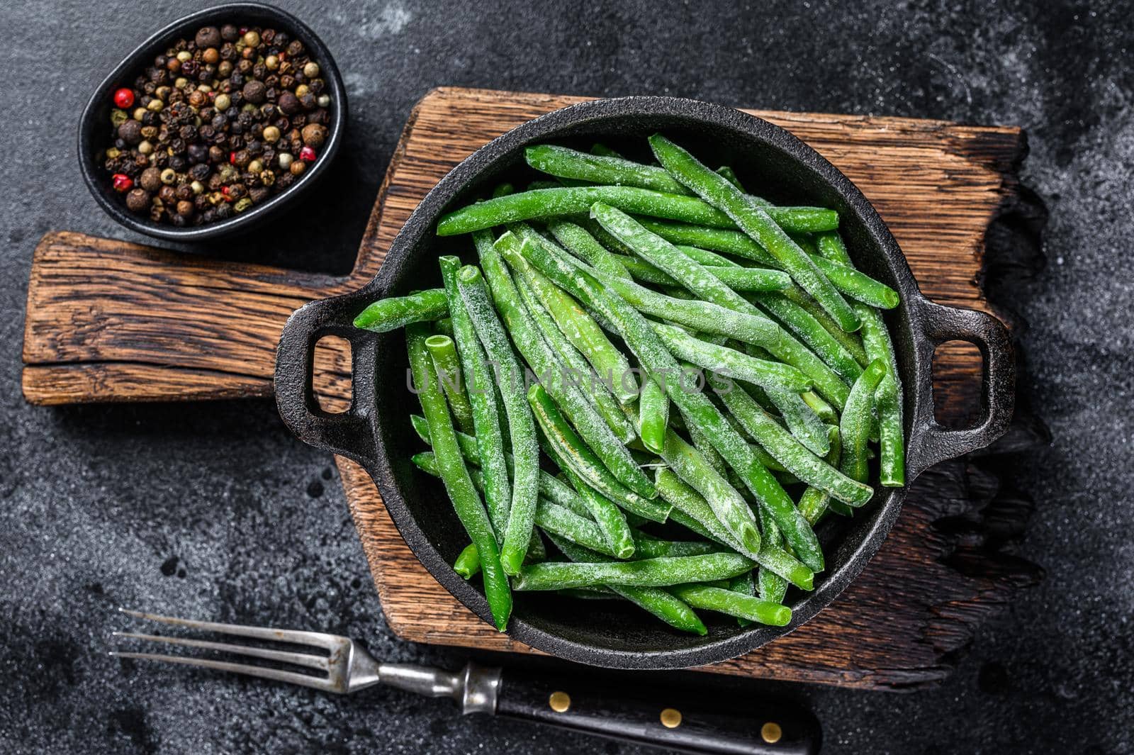 Frozen green beans in a pan. Black background. top view.