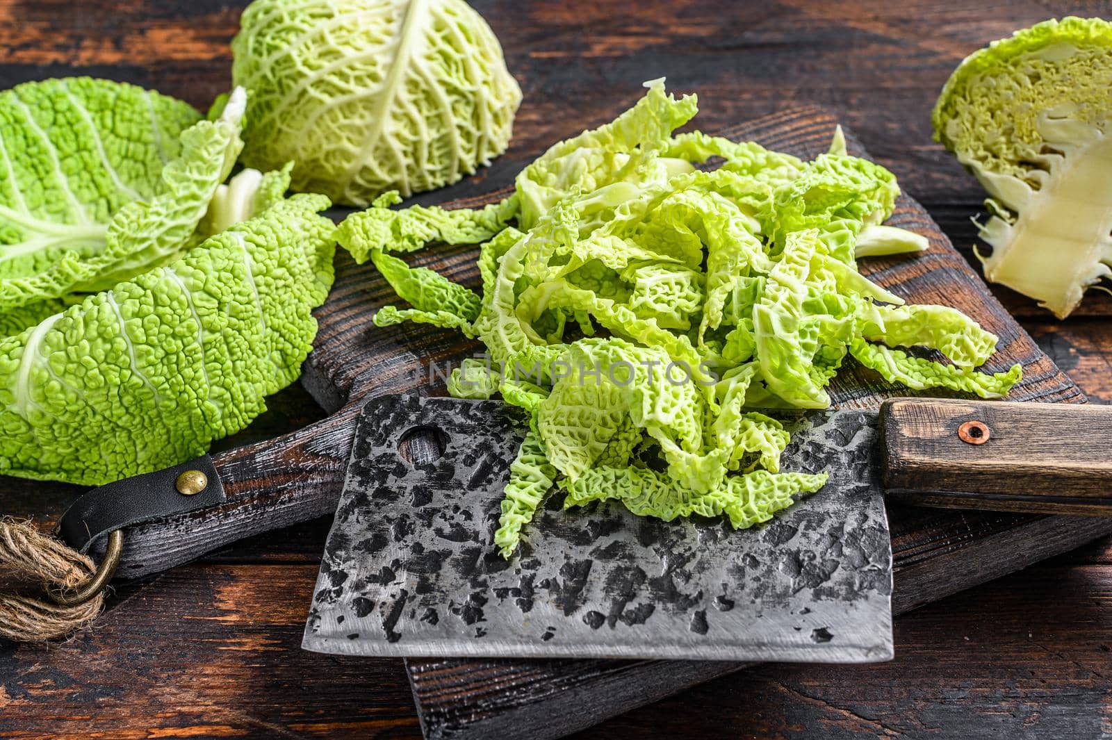 Cut Fresh healthy savoy cabbage on cutting board. Dark wooden background. Top view.