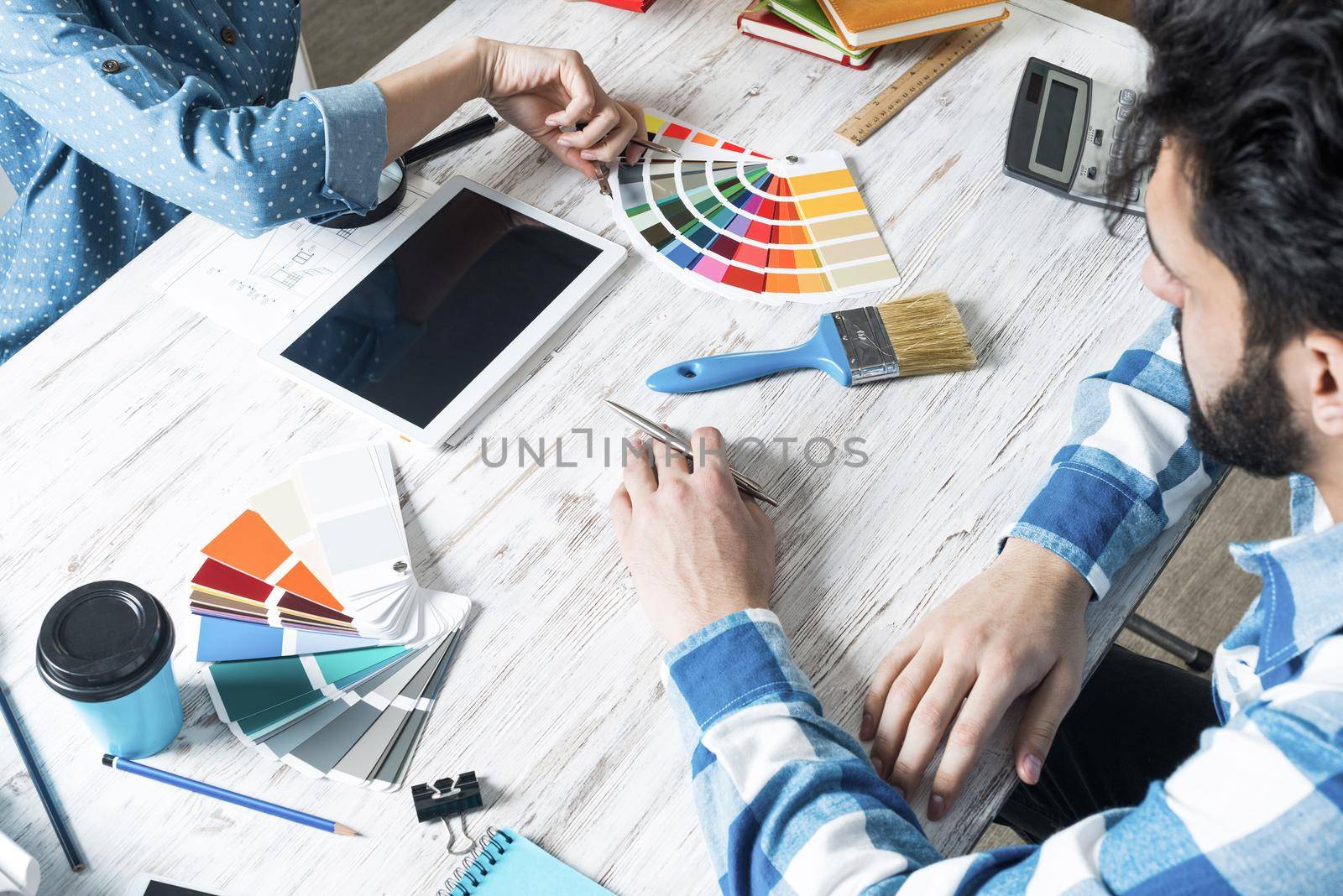 Web designers choosing colors from swatches at desk. Office workplace with tablet computer and color samples. Designing user interface of mobile application. Coloristics and professional visual design