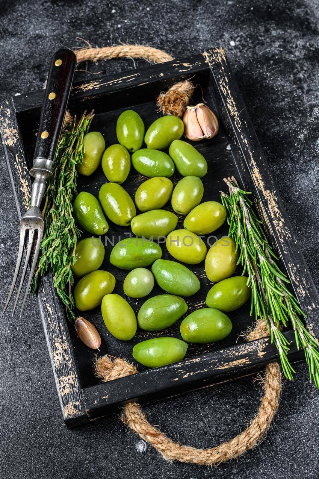 Fresh Green olives in wooden tray with thyme. Black background. Top view by Composter