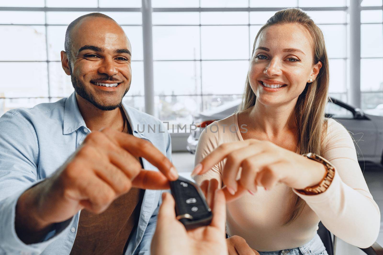Cheerful couple taking keys of their new car in car dealership by Fabrikasimf