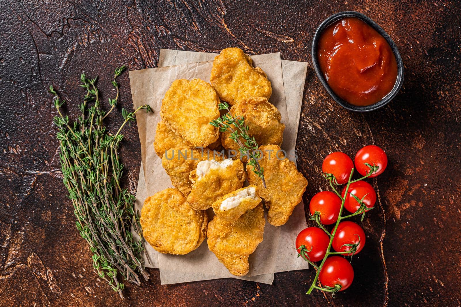 Pile of crispy homemade baked chicken nuggets with ketchup. Dark background. Top view.