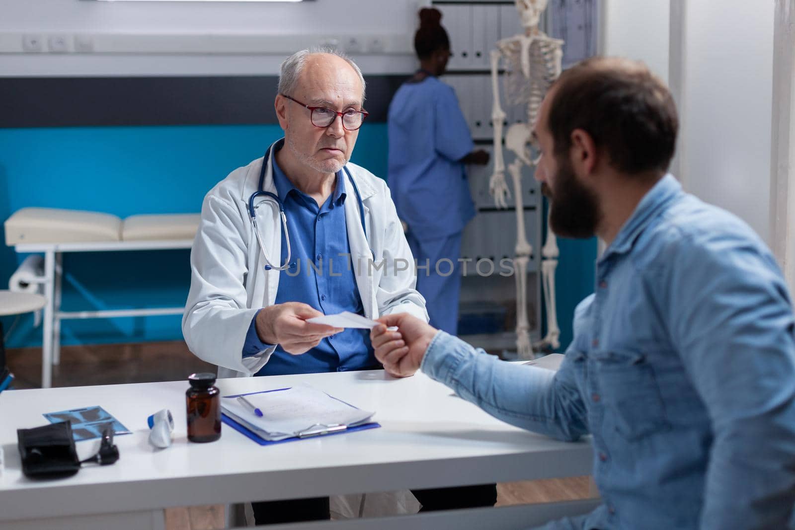Specialist giving prescription paper to sick patient at checkup visit by DCStudio