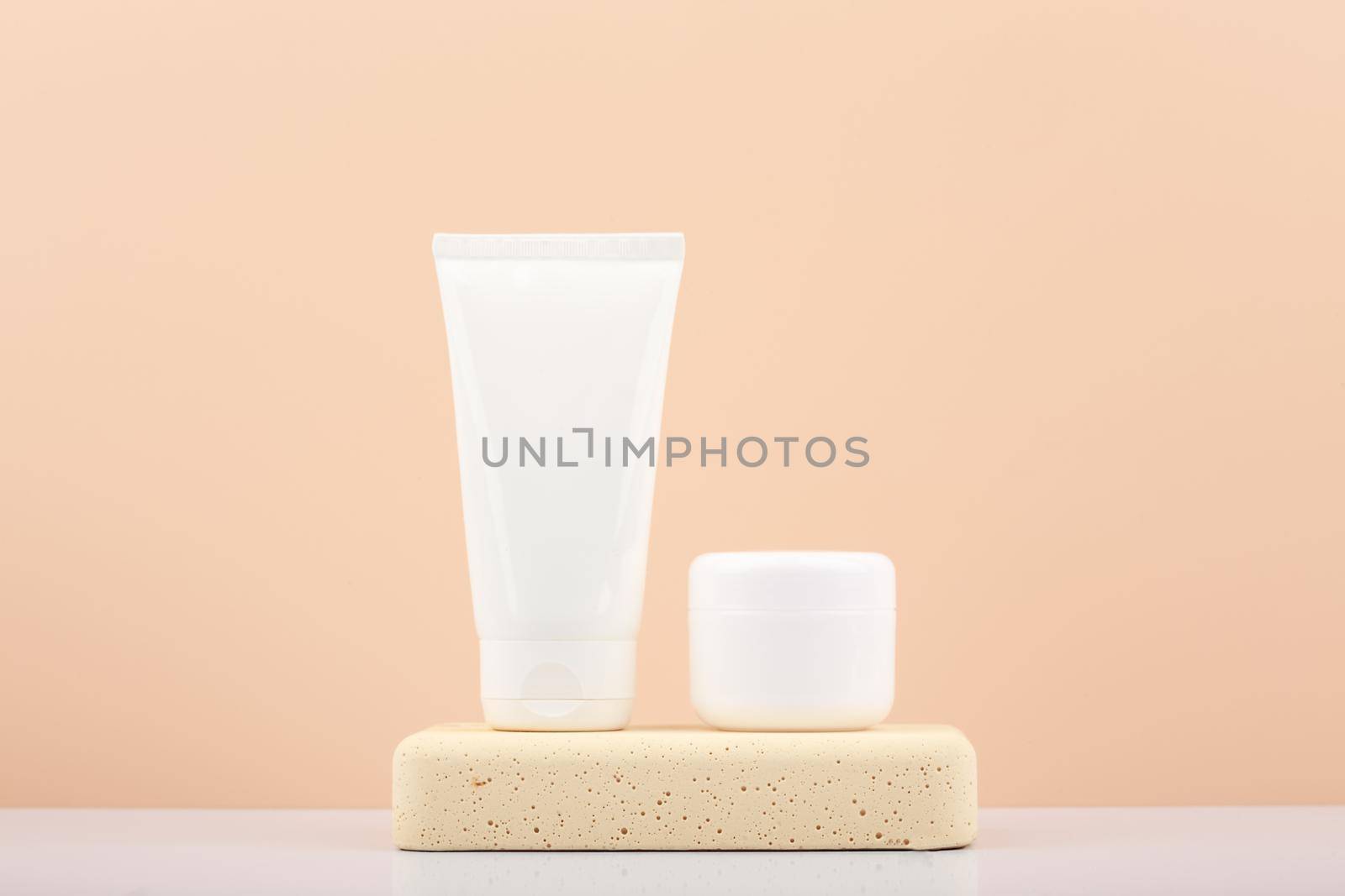 White cosmetic tubes with scrub and mask for face or hand skin on gypsum podium on white table against beige background. by Senorina_Irina