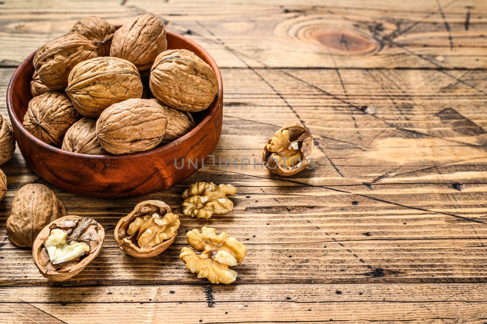 Walnuts in a wooden plate and walnut kernels. Gray background. Top view. Copy space.