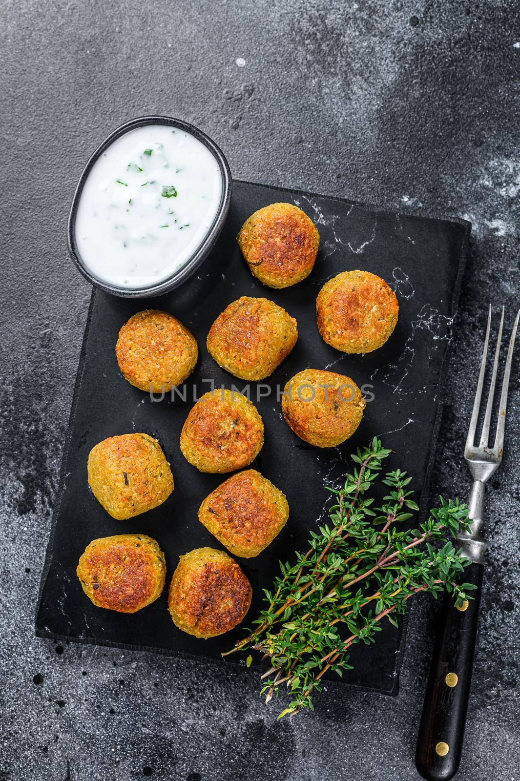 Roasted vegetarian falafel balls from spiced chickpeas with garlic yogurt sauce. Black background. Top view by Composter