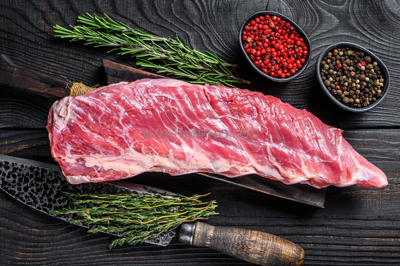 Raw veal calf short spare rib meat with butcher knife. Black wooden background. Top view.