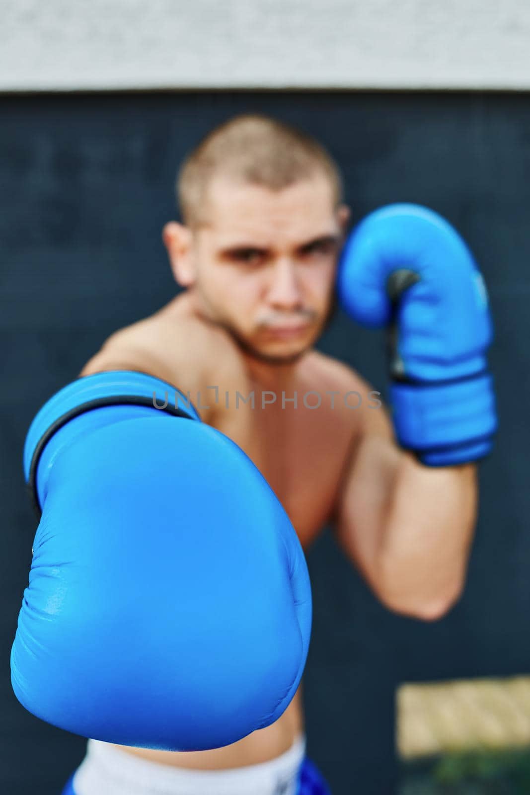 Boxer in blue gloves on the street. He looks into the camera. Beat in the camera