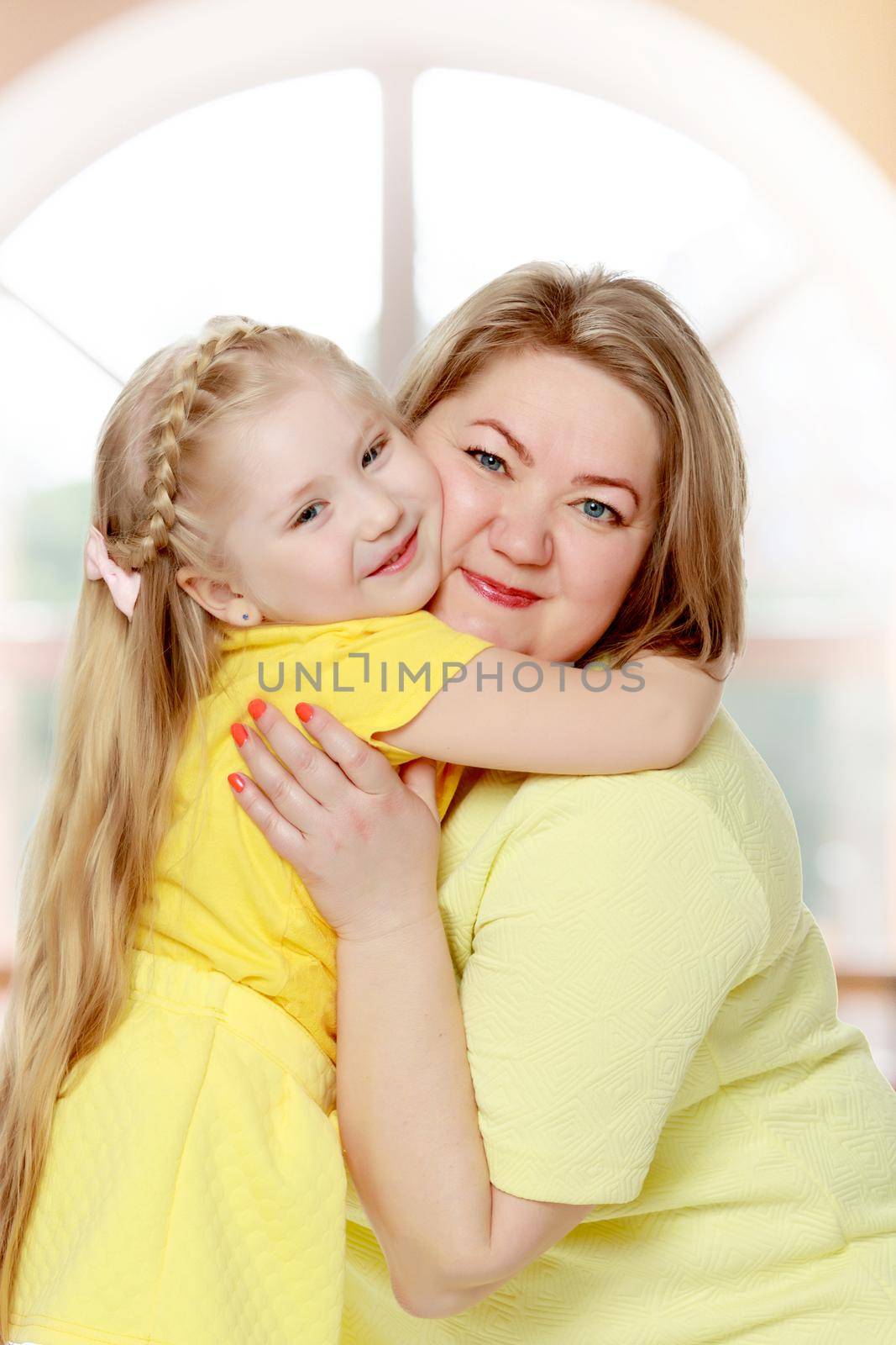 Young blonde mother, gently hugs her favorite little round-faced daughter. Family Idyll.Isolated on white background.