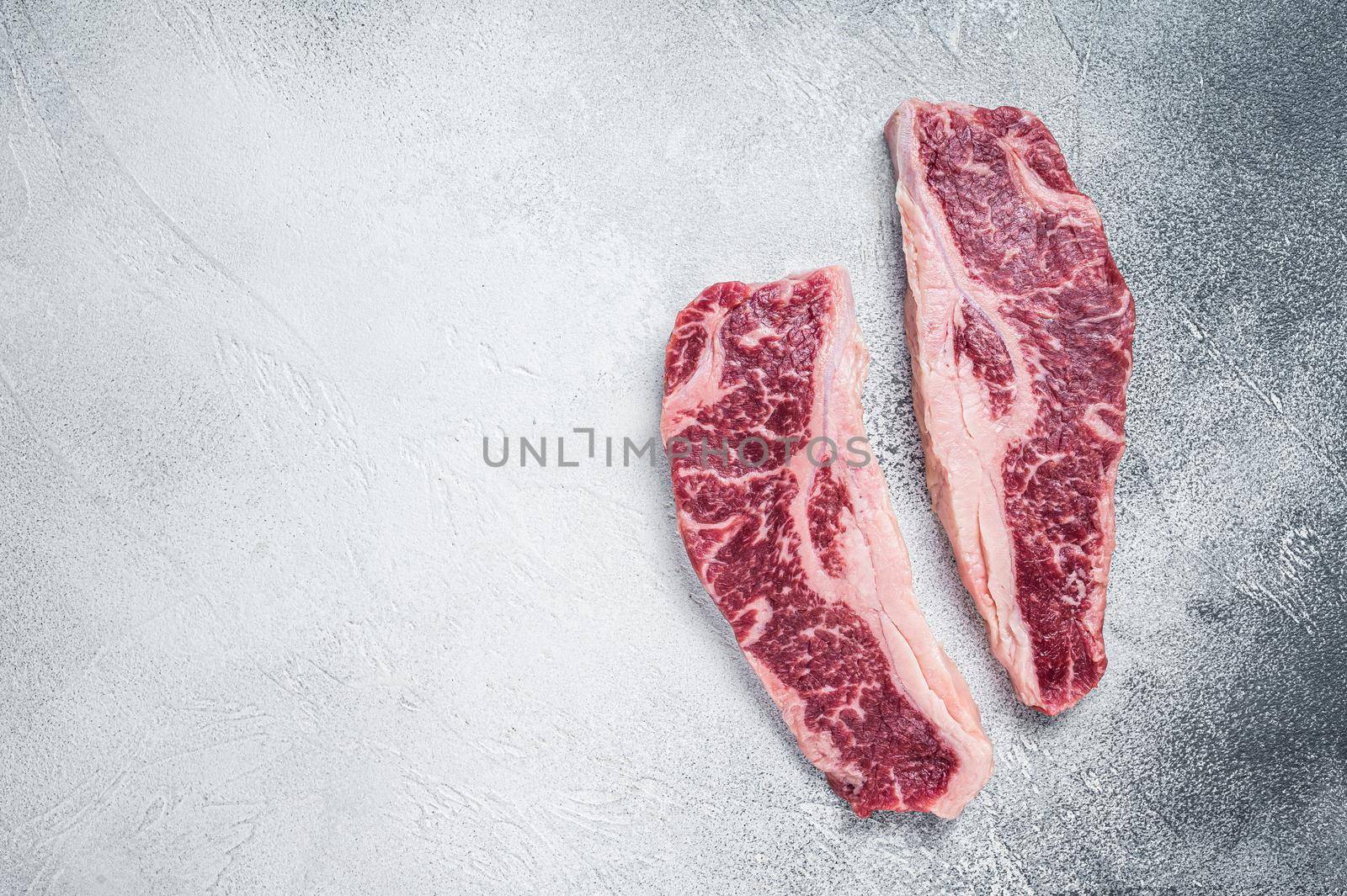 Striploin steak or New York steak, raw beef butchery meat cut. White background. Top view. Copy space by Composter