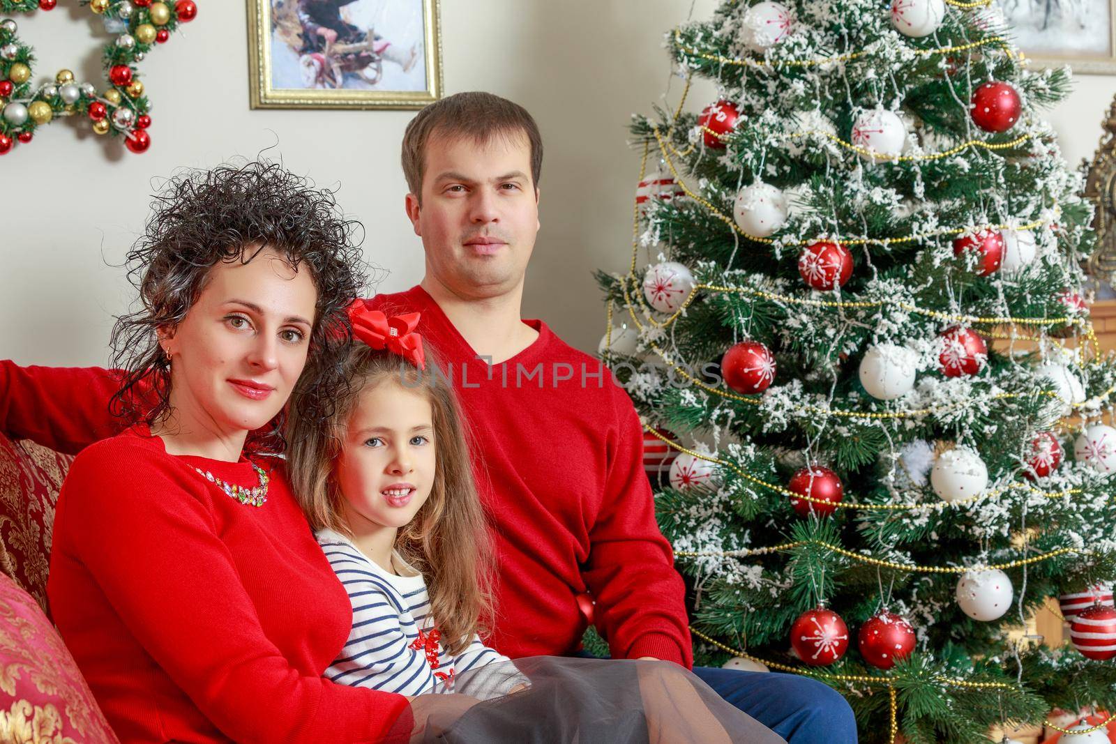 Happy parents with little daughter in a relaxed family atmosphere in the New year.Around the Christmas tree.