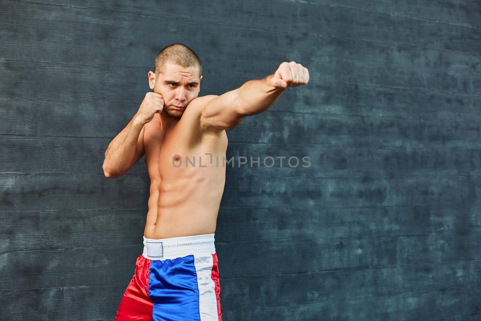 Boxer shorts in athletic training outdoors. He stands in a fighting stance. The young man works off a blow