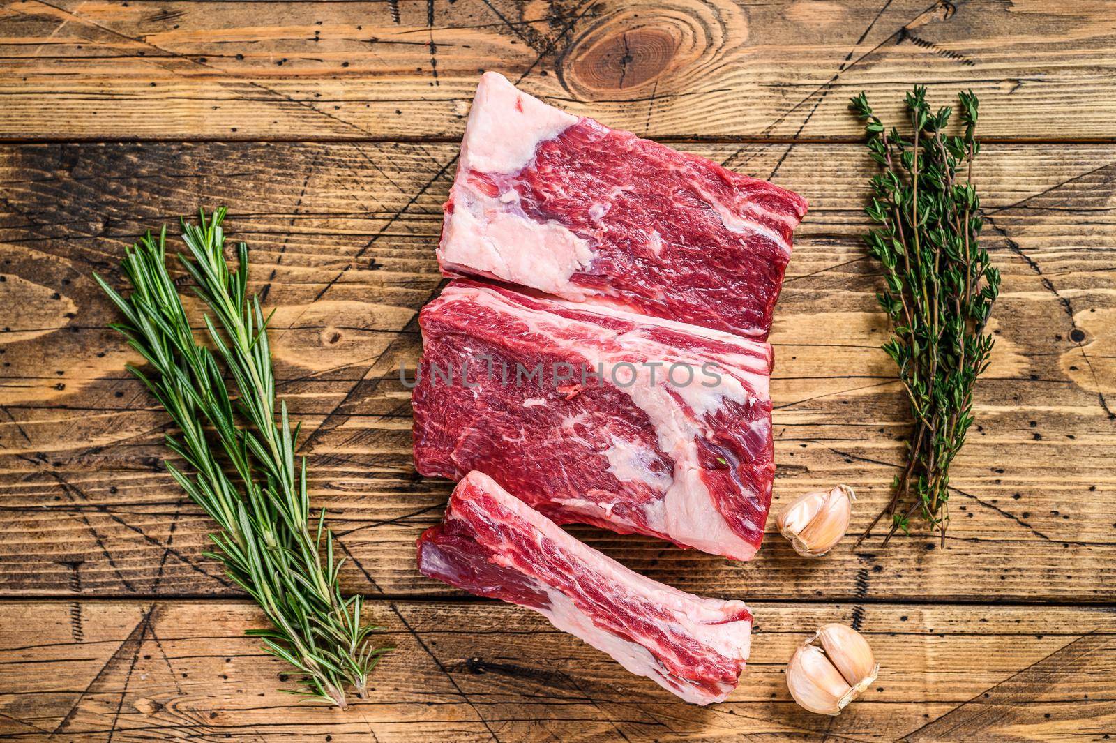 Fresh Beef short ribs on butcher wooden table. Wooden background. Top view by Composter