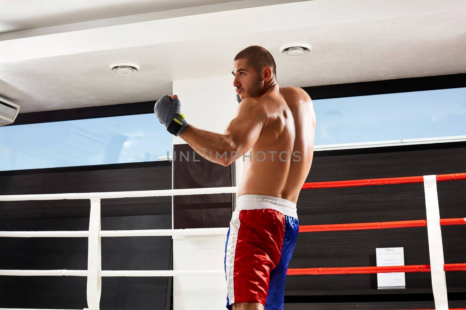 Boxer in grey gloves warming up in the gym. naked torso.