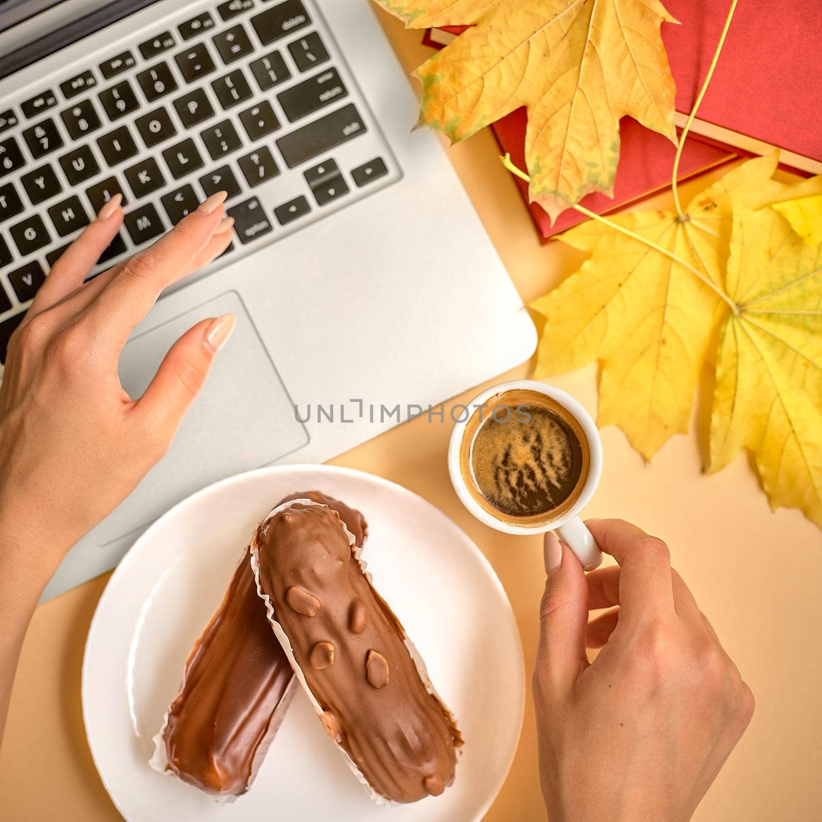 The girl makes a coffee break in the workplace. Profiteroles with cream with a Cup of coffee and a laptop by izik