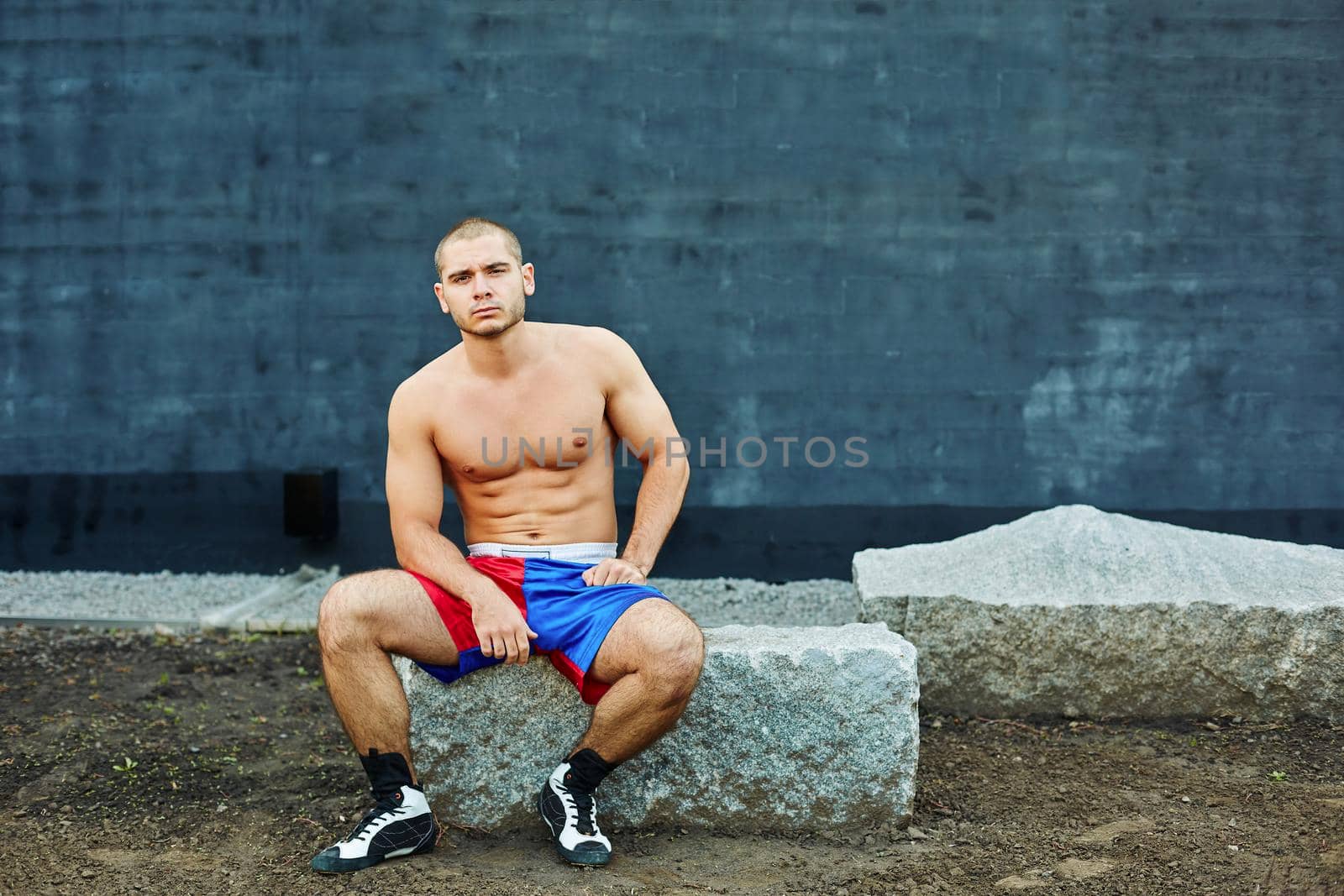 The sportsman has a rest, sitting on a rock. He looks into the camera