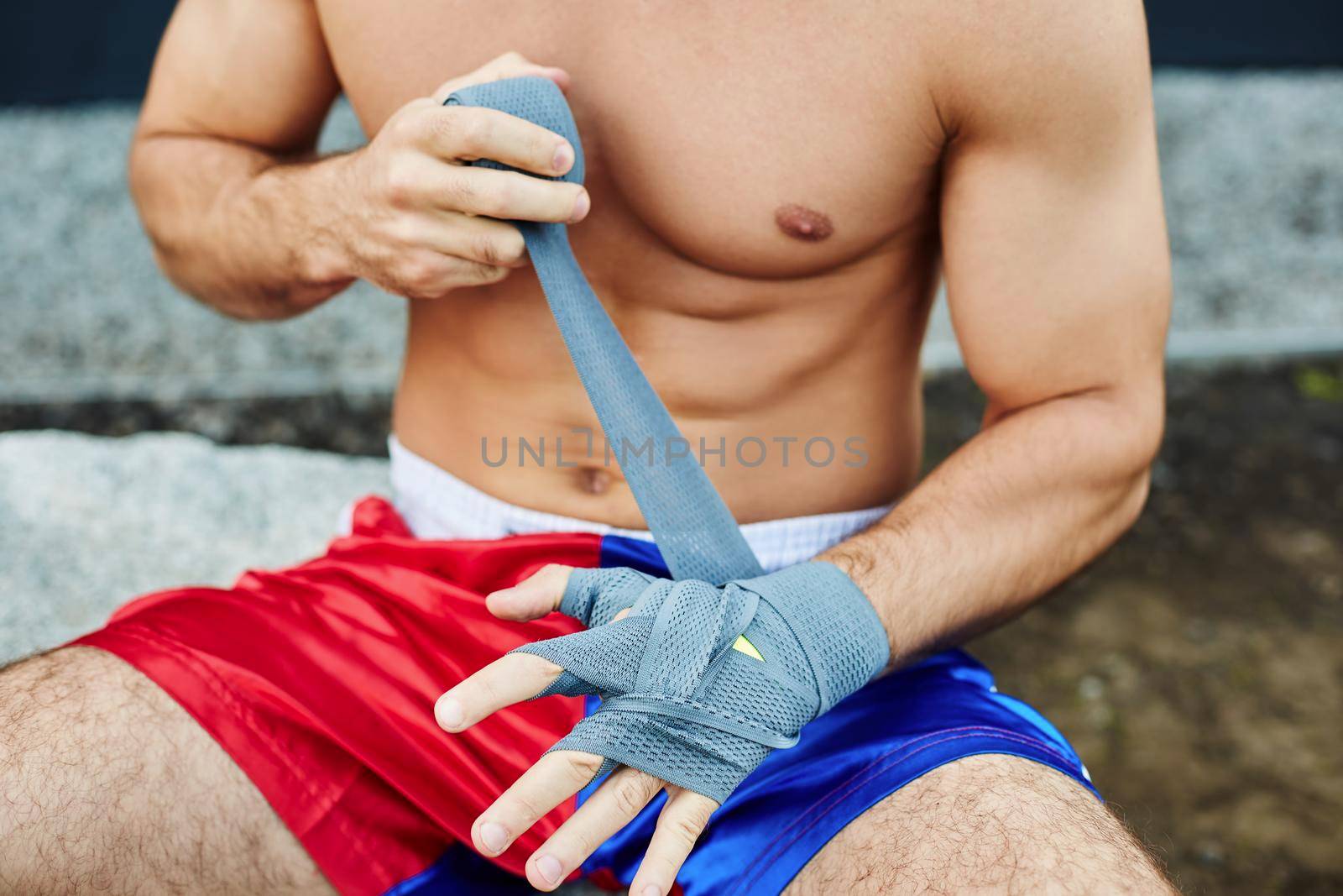 Close up of fit man wearing bandage on his hand. Nude torso