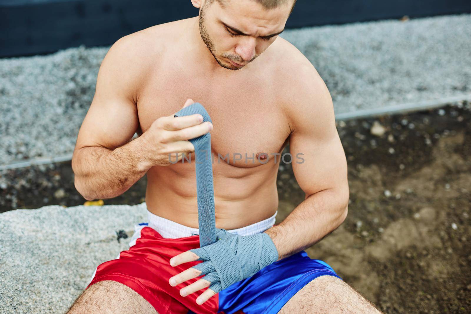 Close up of fit man wearing bandage on his hand. Nude torso
