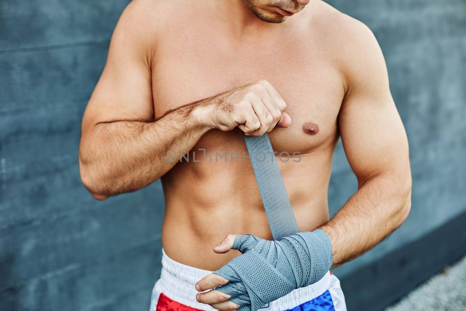 Close up of fit man wearing bandage on his hand. Nude torso