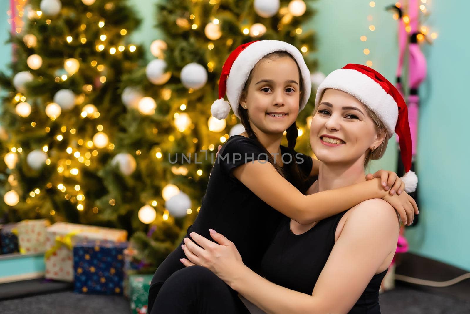 A young and happy mother and daughter in Christmas hats