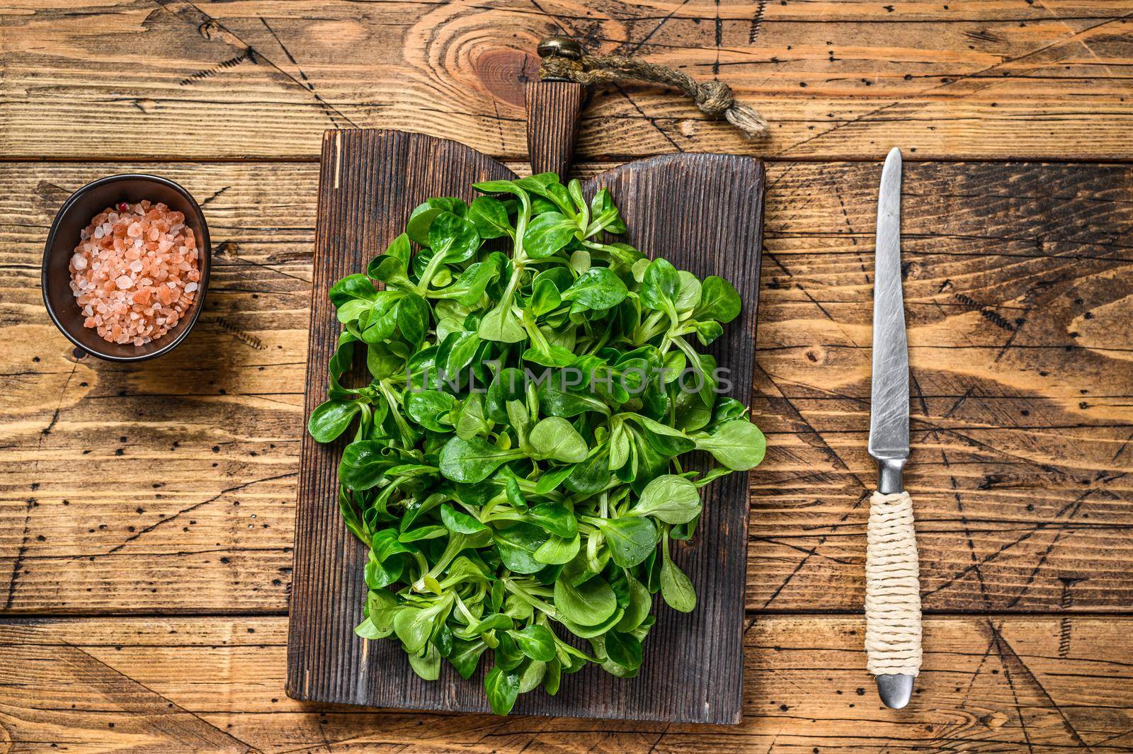 Fresh Raw green lambs lettuce Corn salad leaves on a wooden cutting board. wooden background. Top view.