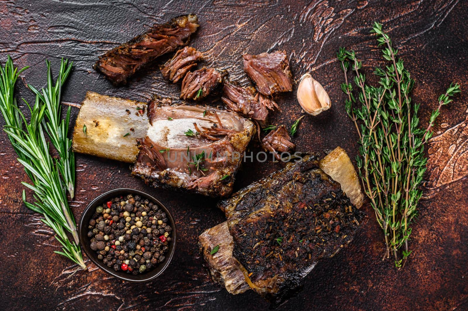 BBQ Grilled short beef ribs on a kitchen table. Dark background. Top view by Composter