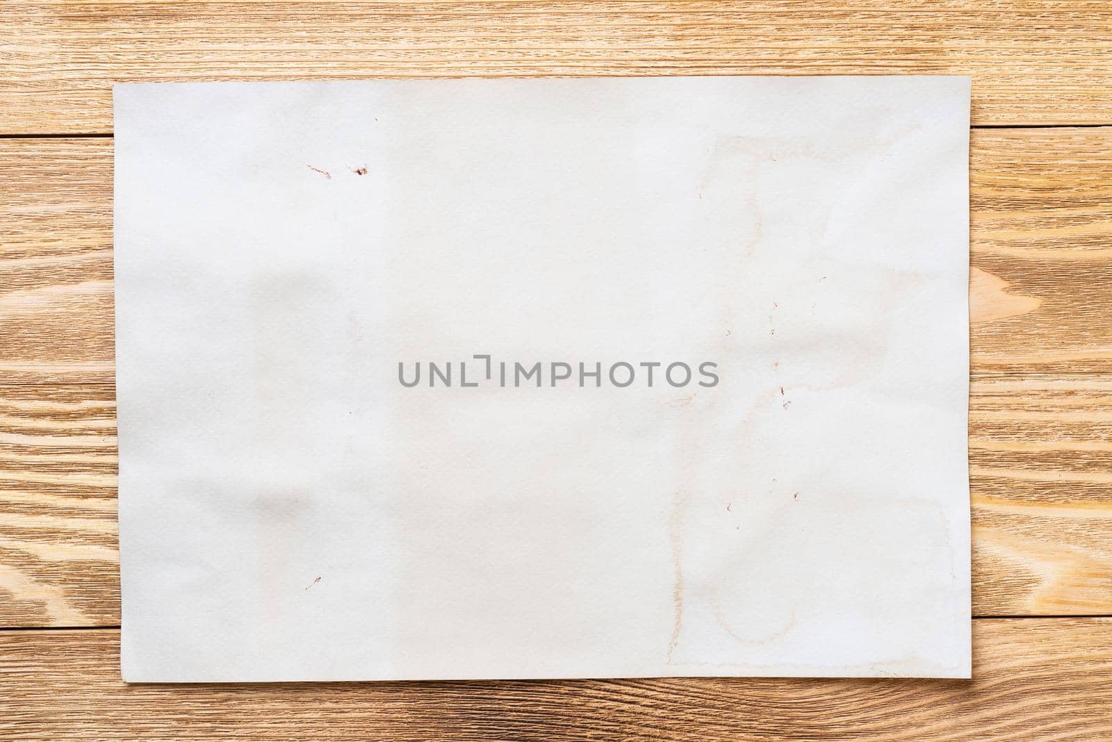 Minimal wooden desk workplace with blank paper. Flat lay textured natural wooden background. Vintage copy space for creative design and advertising. Close up A4 format paper on wooden surface.