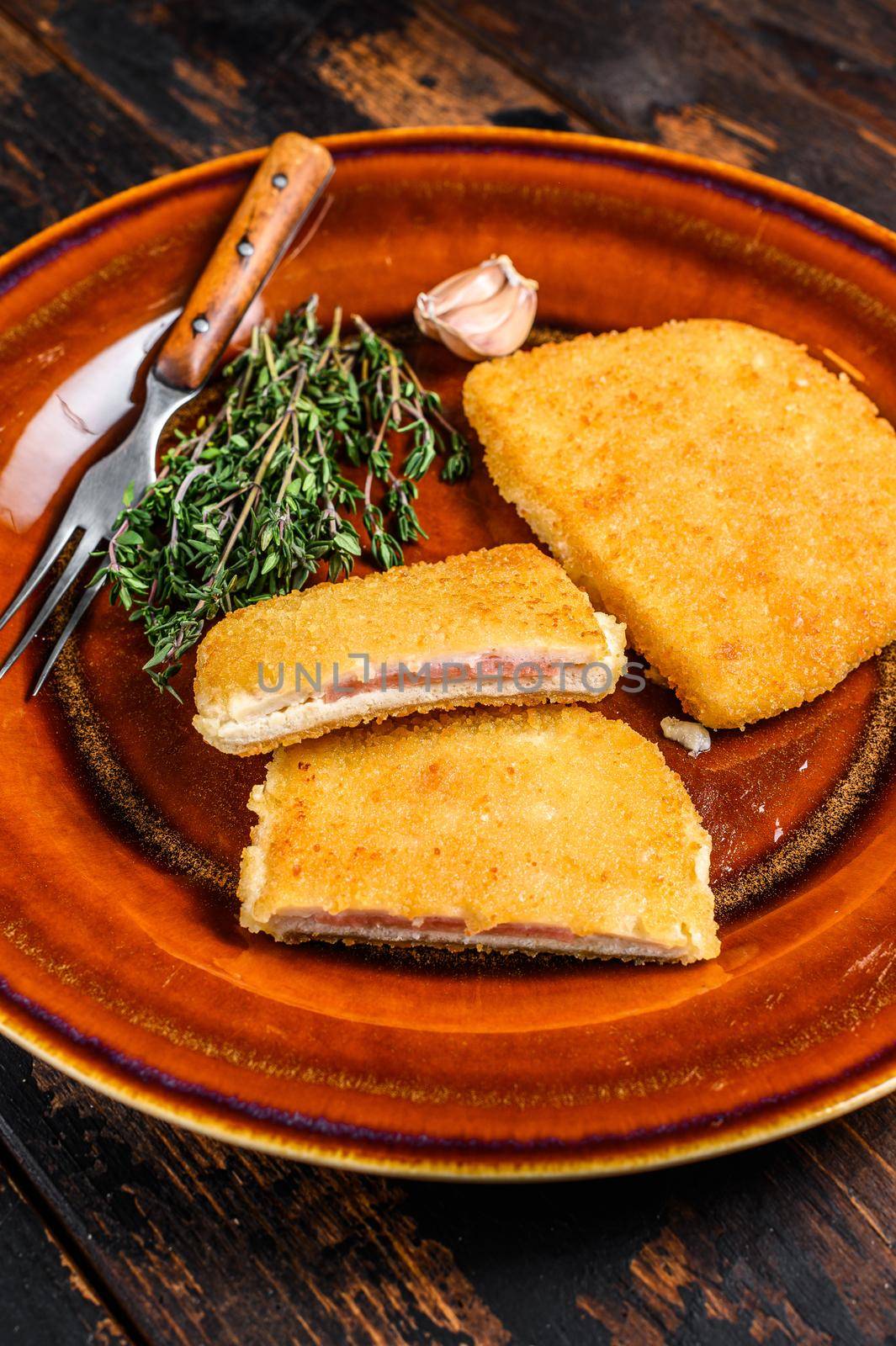 Chicken cordon bleu meat roll cutlet with ham and cheese. Dark wooden background. Top view.