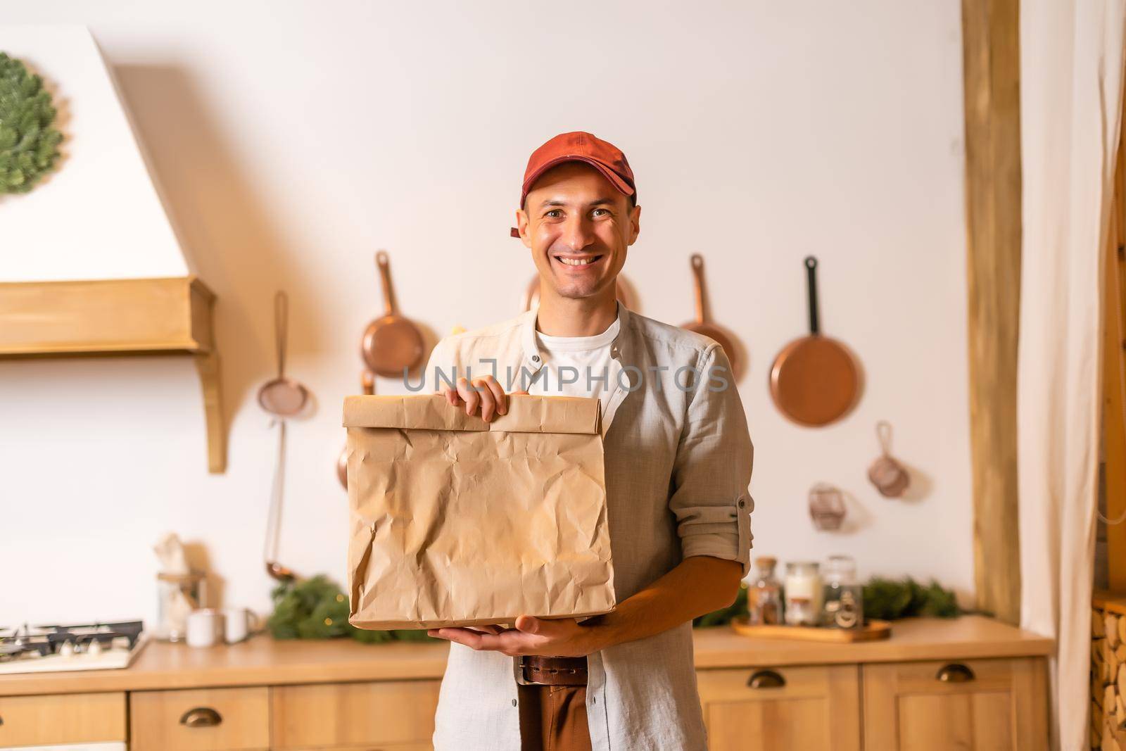 a delivery man with a package of food stands in a Christmas interior