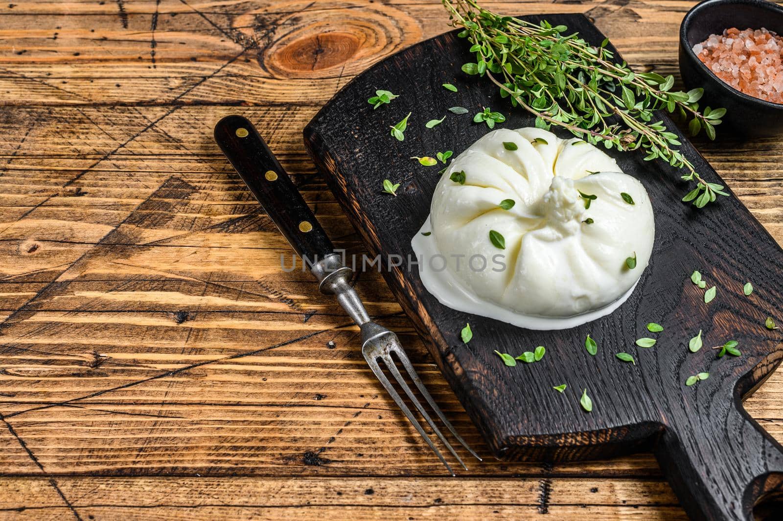 Cheese Burrata mozzarella on a wooden cutting board. wooden background. Top view. Copy space by Composter