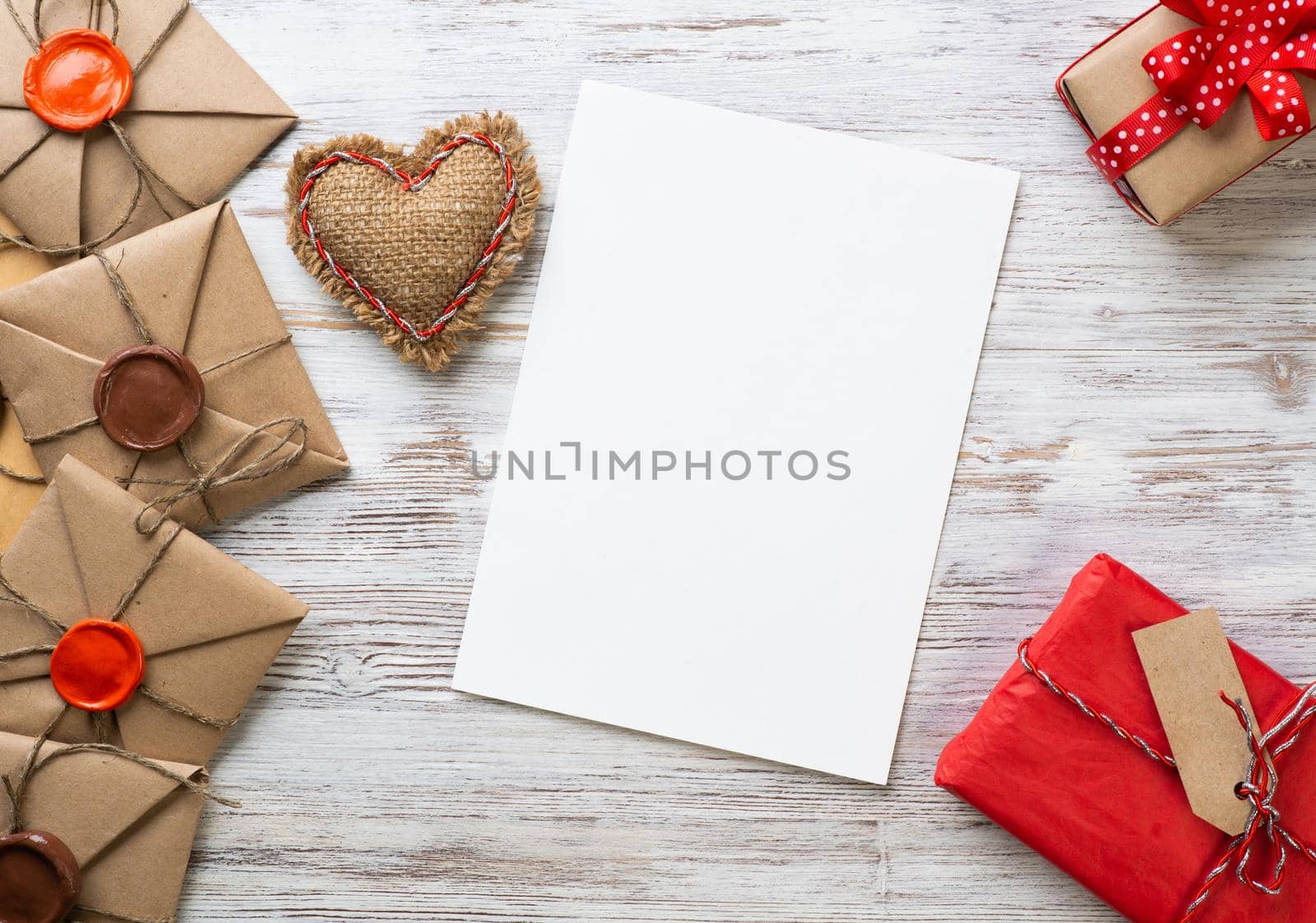 Flat lay composition with handmade fabric heart and gift box. Blank sheet of white paper on wooden surface. Romantic Saint Valentine's day congratulation. Merry Christmas and Happy New Year.