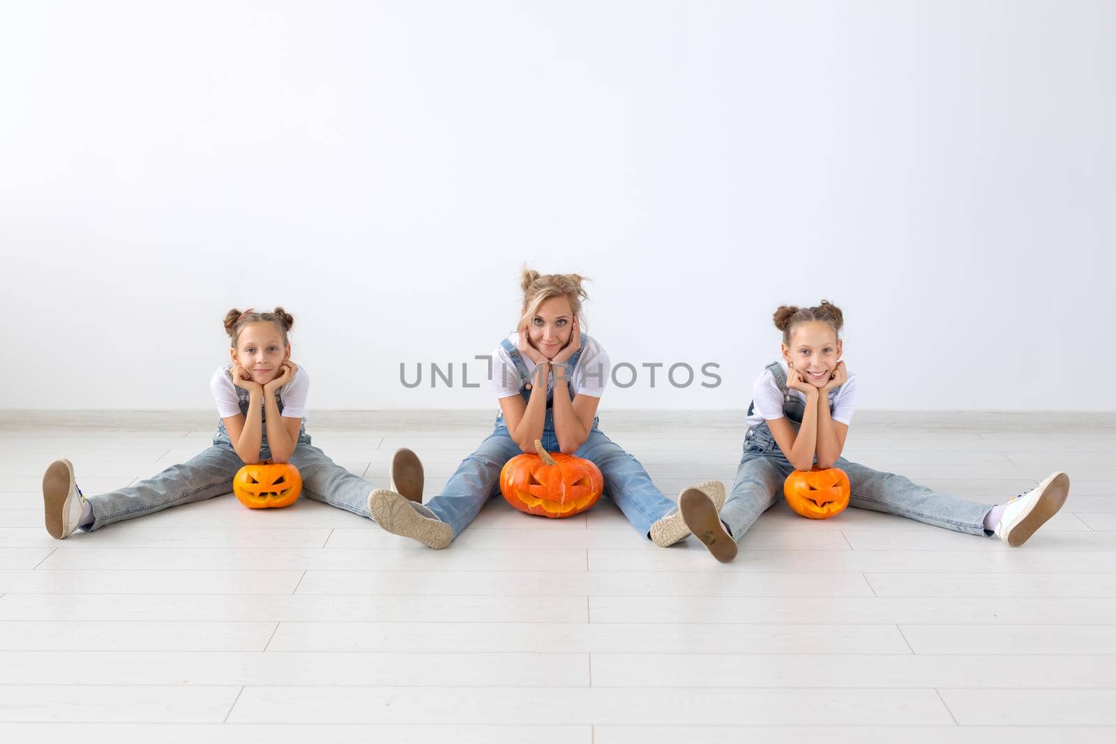 Happy halloween and holidays concept - A mother and her daughters with pumpkins. Happy family preparing for Halloween