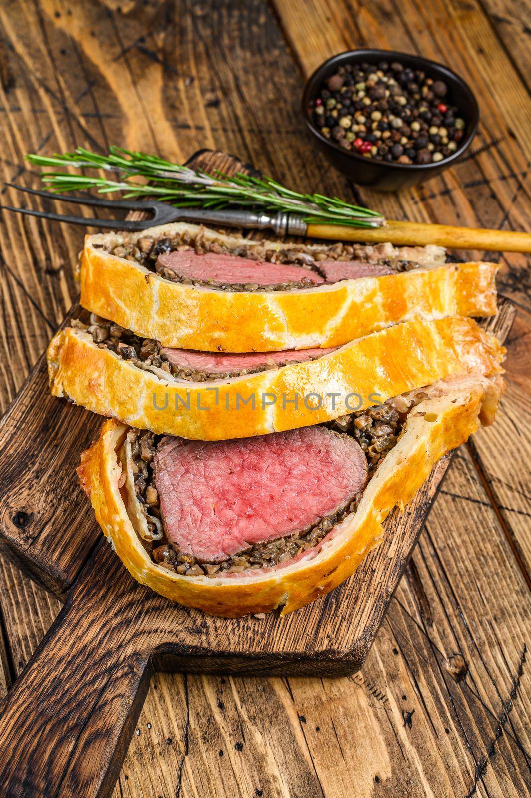 Sliced Beef Wellington pastry on a wooden cutting board. wooden background. Top view by Composter