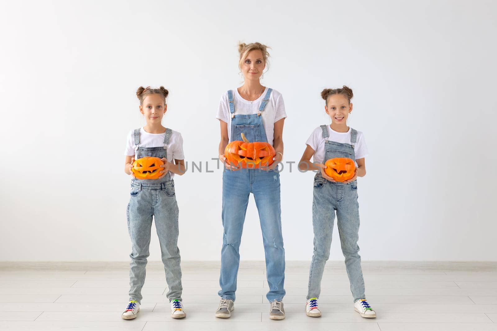 Happy halloween and holidays concept - A mother and her daughters with pumpkins. Happy family preparing for Halloween. by Satura86