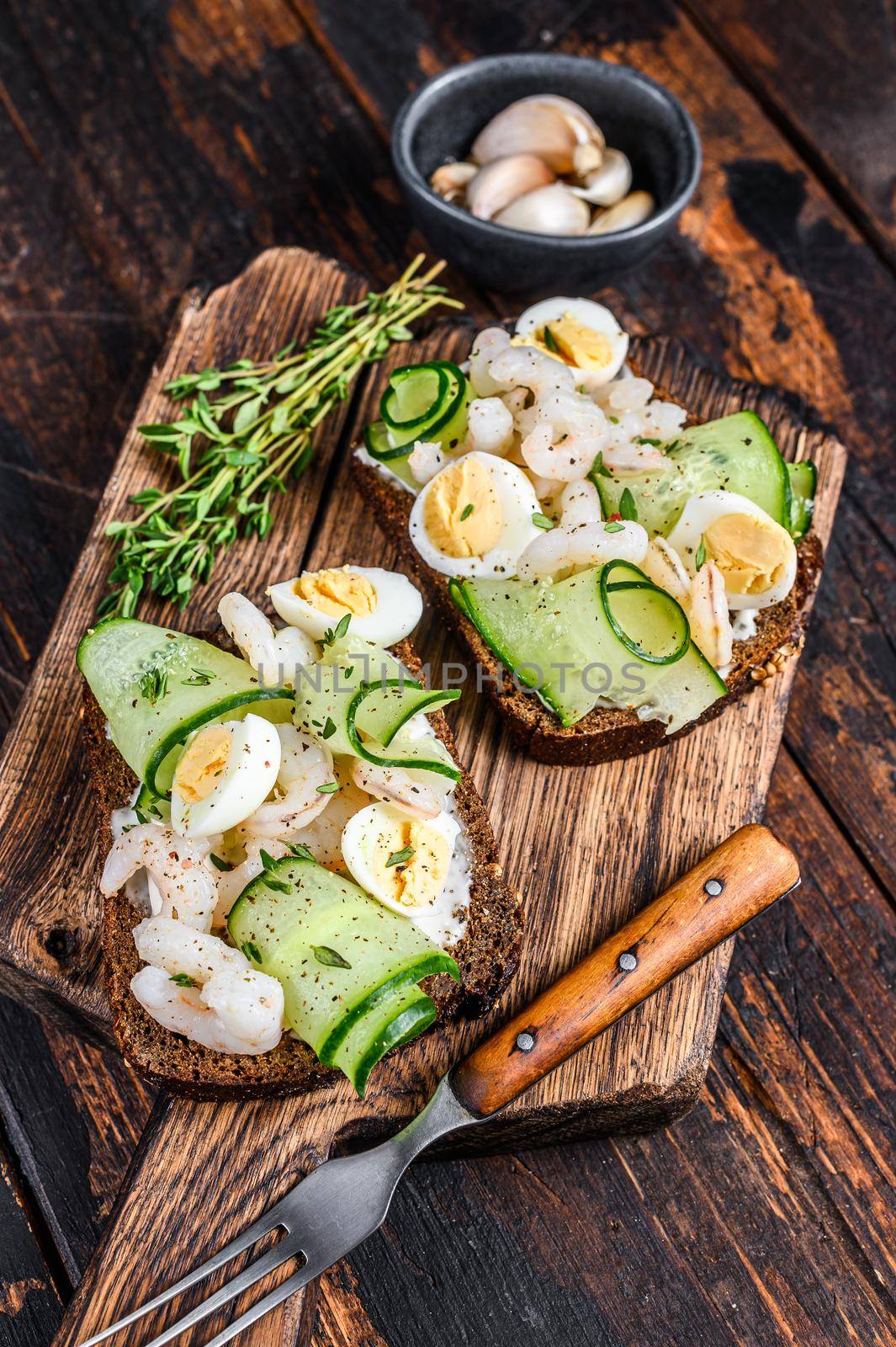 Sandwiches with shrimp, prawns, quail eggs and cucumber on rye bread. Dark Wooden background. top view by Composter