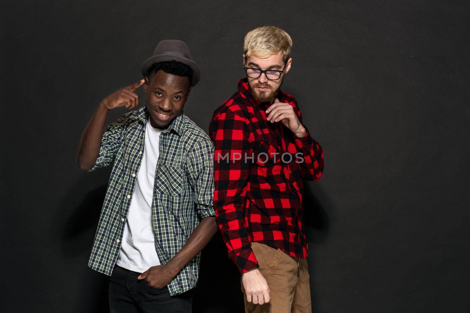 Studio lifestyle portrait of two best friends hipster boys going crazy and having great time together. On black background. Belt portrait