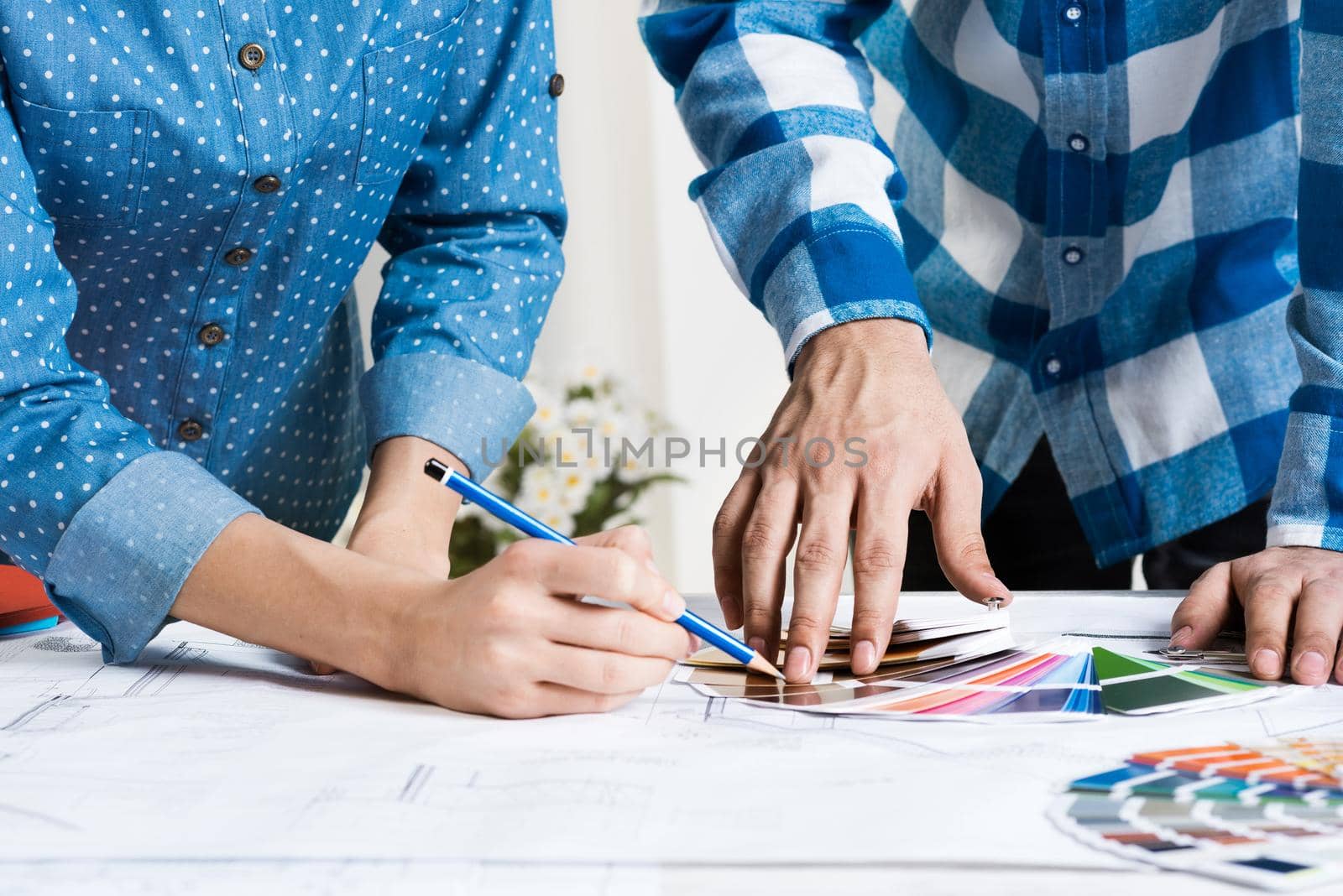 Designers selecting color palette for design project. Human hands, technical drawing and color swatches on desk. Interior design, decoration and renovation. Brainstorming, teamwork and creativity.