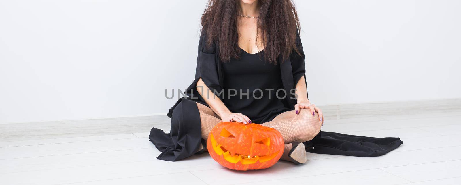 Halloween and masquerade concept - Beautiful young woman posing with Pumpkin Jack-o'-lantern.