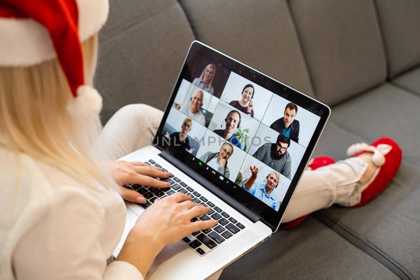 A young smiling woman wearing red Santa Claus hat making video call on social network with family and friends on Christmas day. by Andelov13