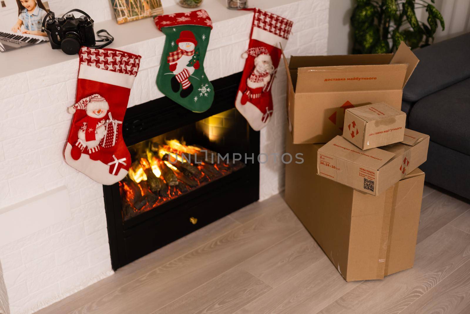 KYIV, UKRAINE - November 16, 2020: boxes Nova Poshta with delivery of Christmas gifts lie near the fireplace by Andelov13