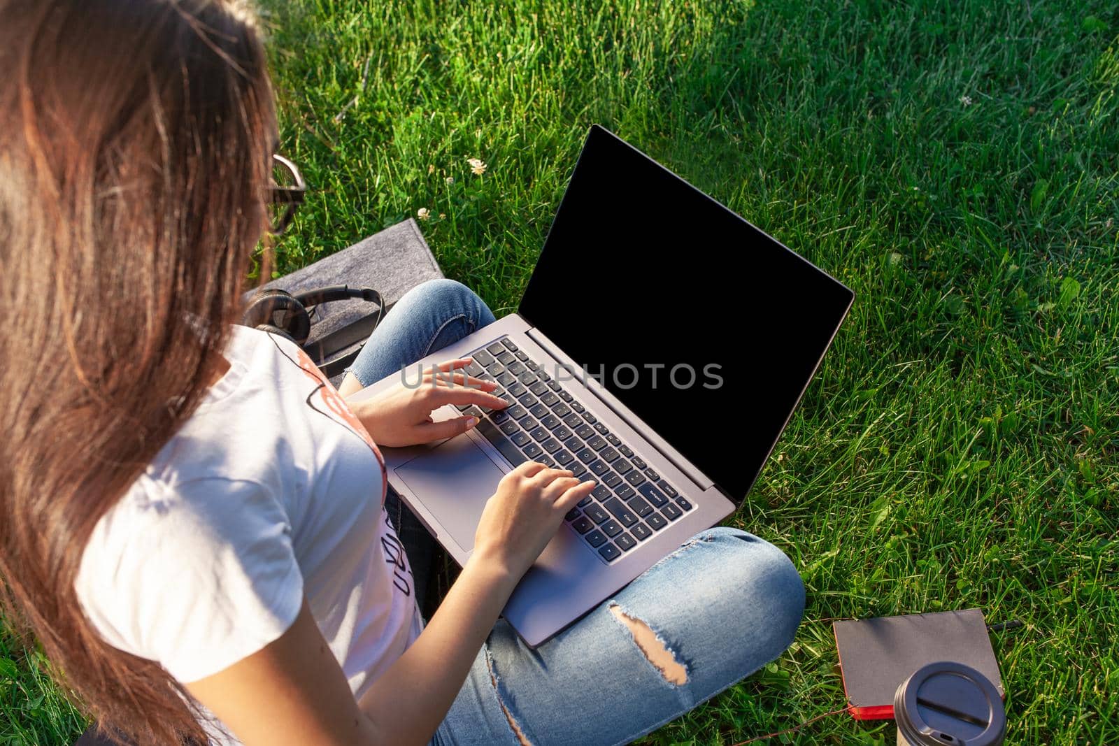 Close up hands on keyboard. Woman working on laptop pc computer with blank black empty screen to copy space in park on green grass sunshine lawn outdoors. Mobile Office. Freelance business concept