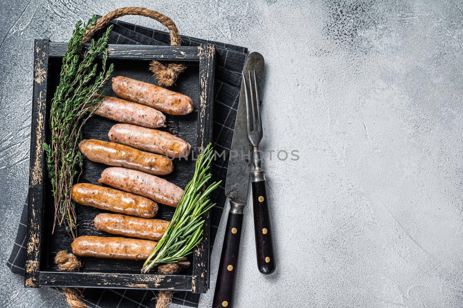 Roasted Bratwurst Hot Dog sausages in a wooden tray with herbs. White background. Top View. Copy space by Composter