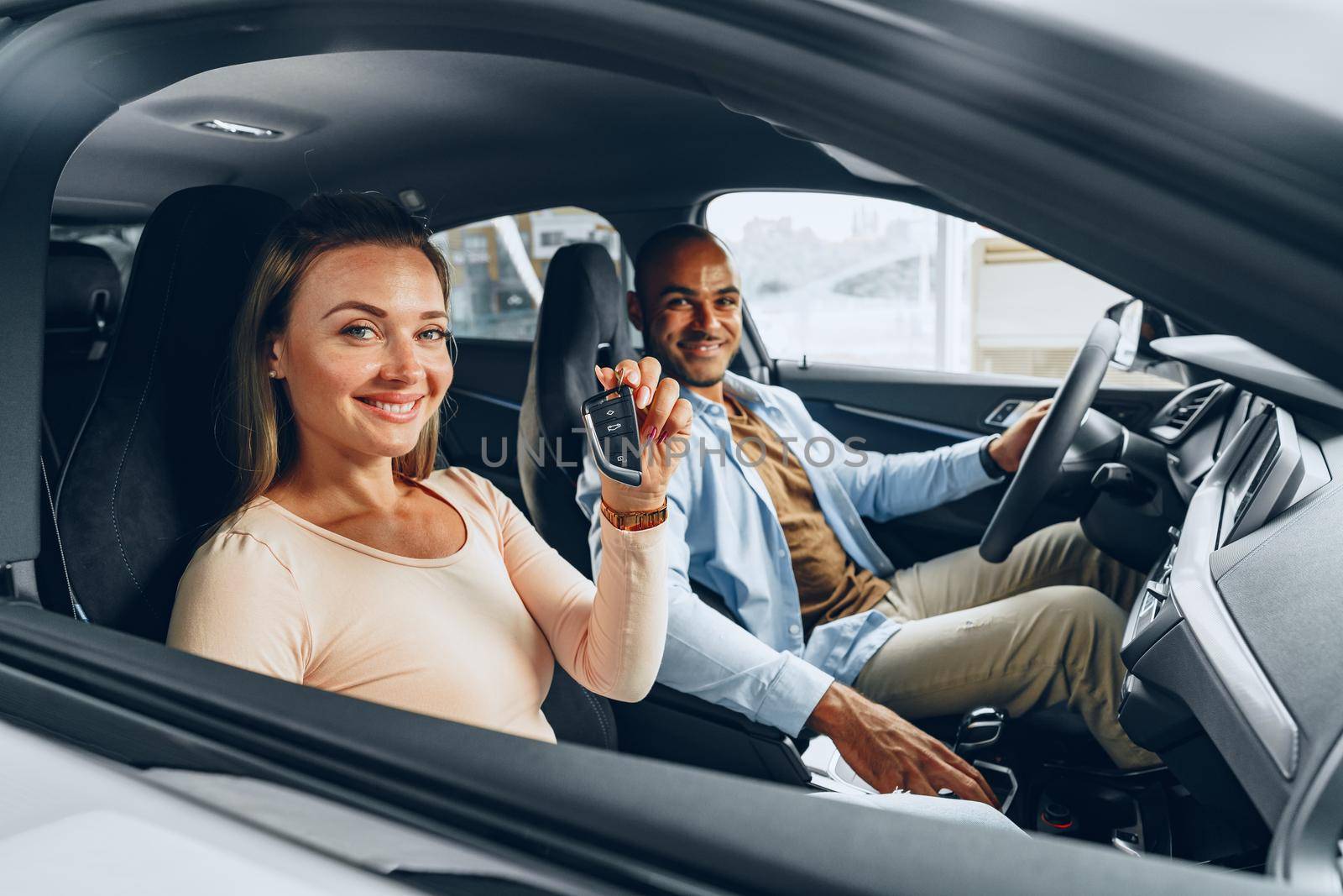 Happy excited couple or family buying a new car and showing keys