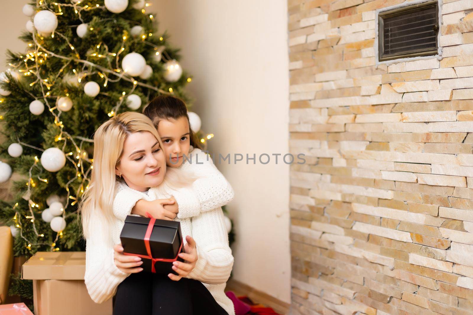 Daughter with her mother near the Christmas tree.