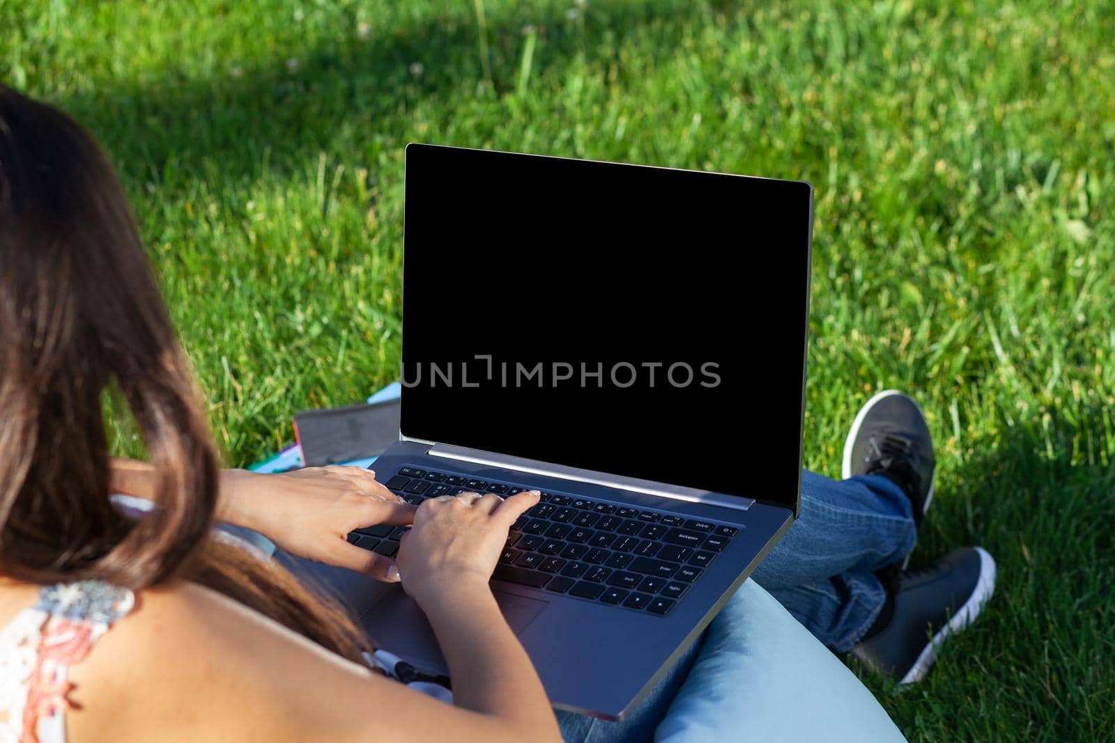 Close up hands on keyboard. Woman working on laptop pc computer with blank black empty screen to copy space in park on green grass sunshine lawn outdoors. Mobile Office. Freelance business concept