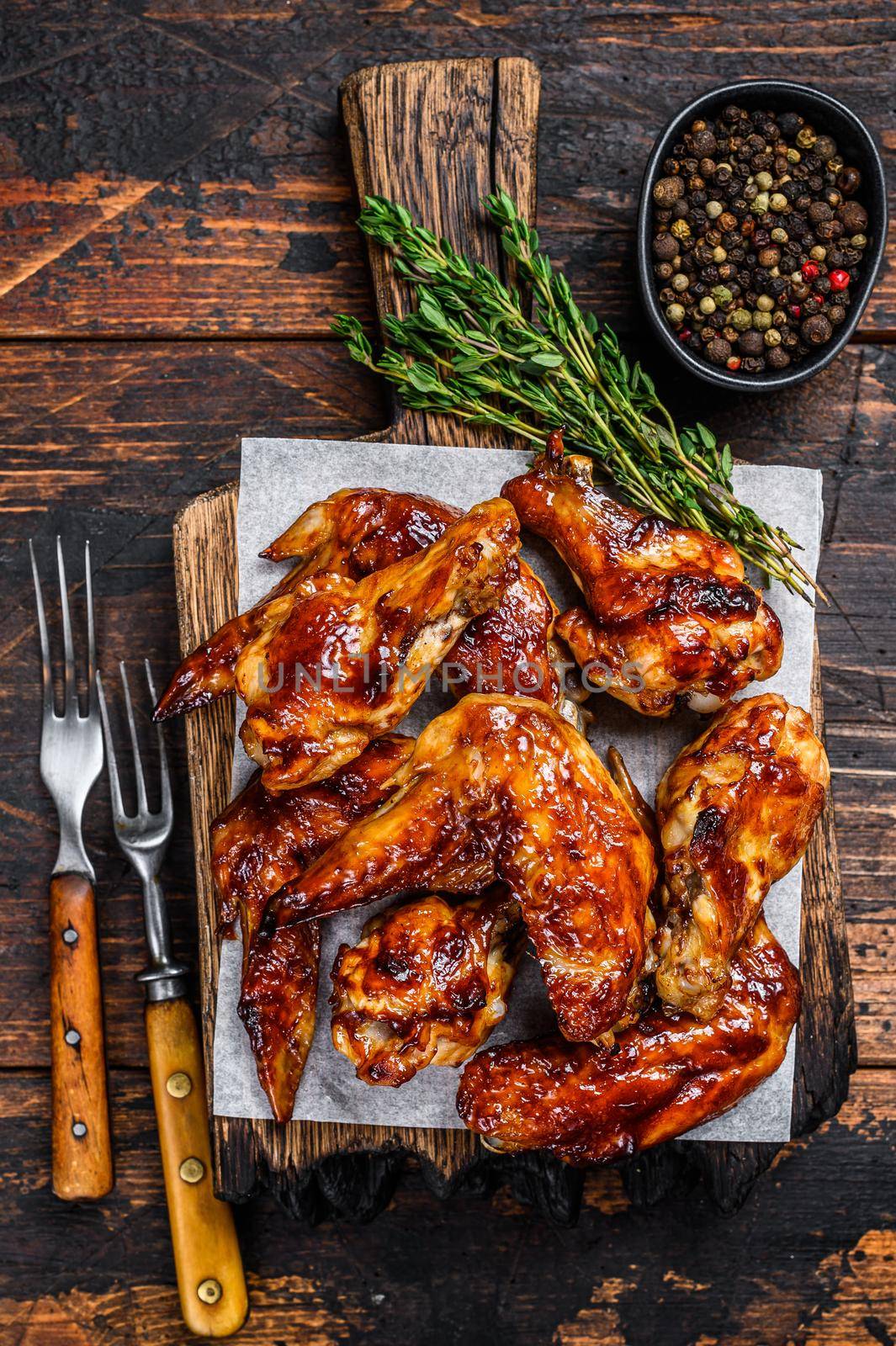 Baked Bbq chicken wings with dip sauce. Dark wooden background. Top view.